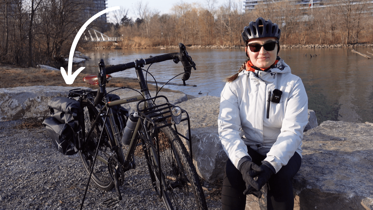 agnieszka sitting next to her kona sutra touring bike, an arrow is pointing towards rear panniers